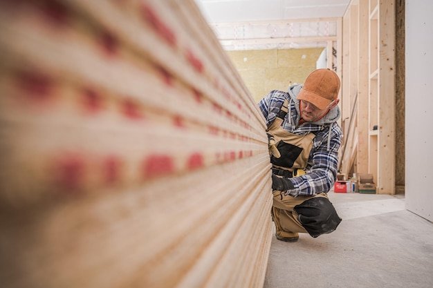 Carpenter Looks At Wooden Boards Needed For Job