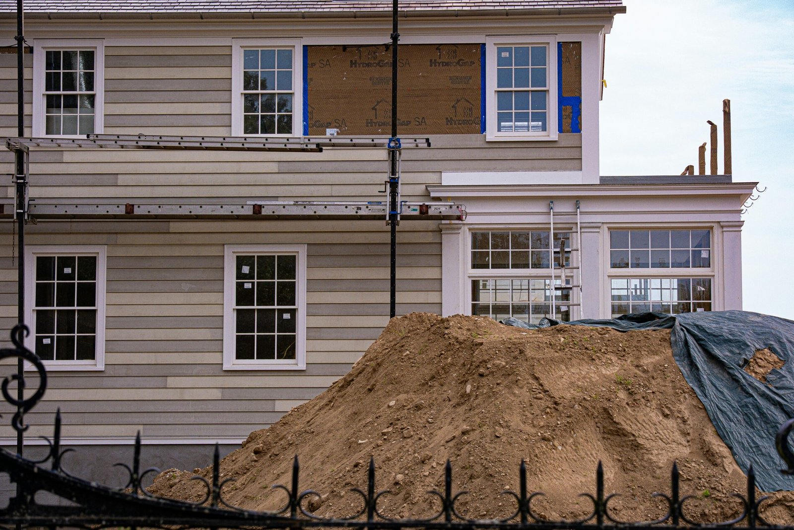 House under renovation with scaffolding and dirt pile.