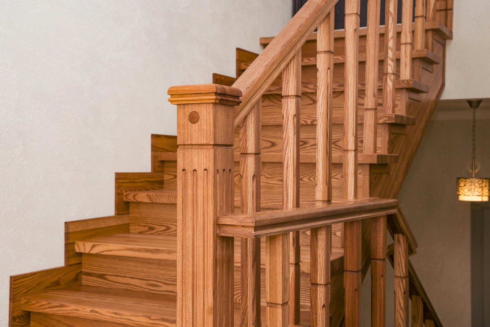 Wooden staircase with ornate balusters and newel post.