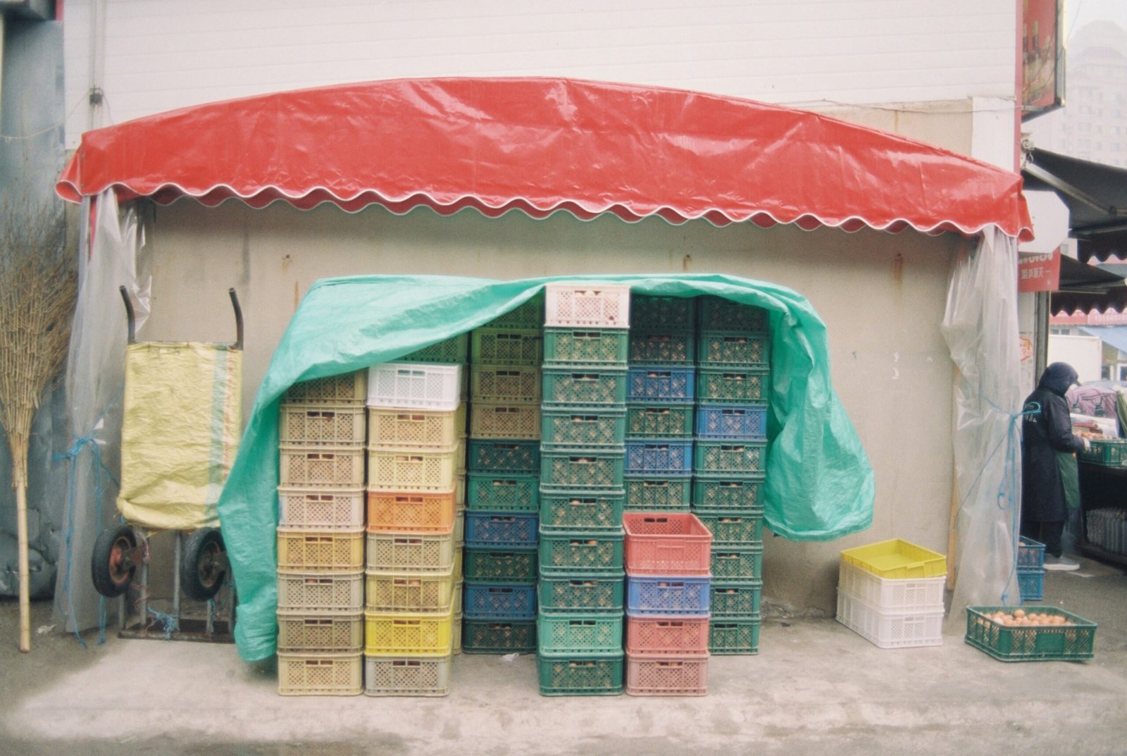 Produce crates are stacked underneath a red awning.