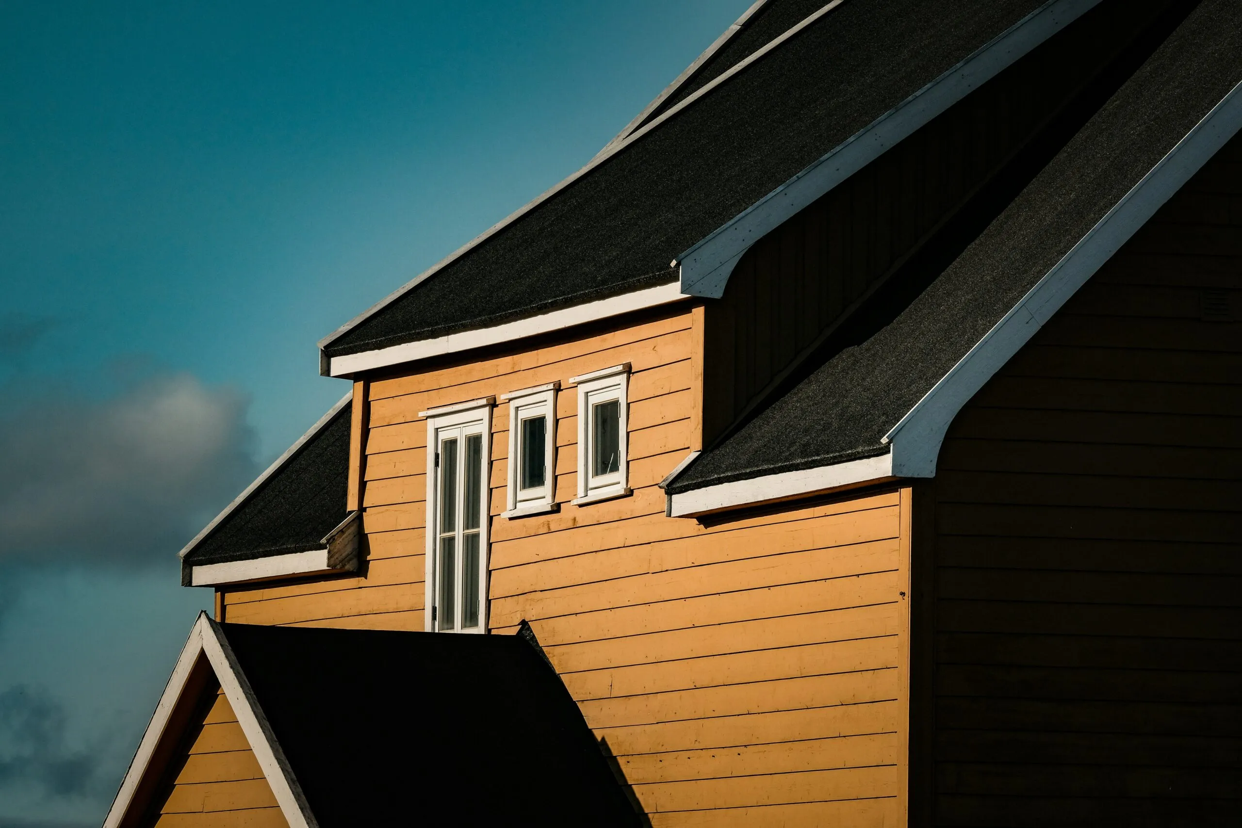 A yellow house with black roofs.