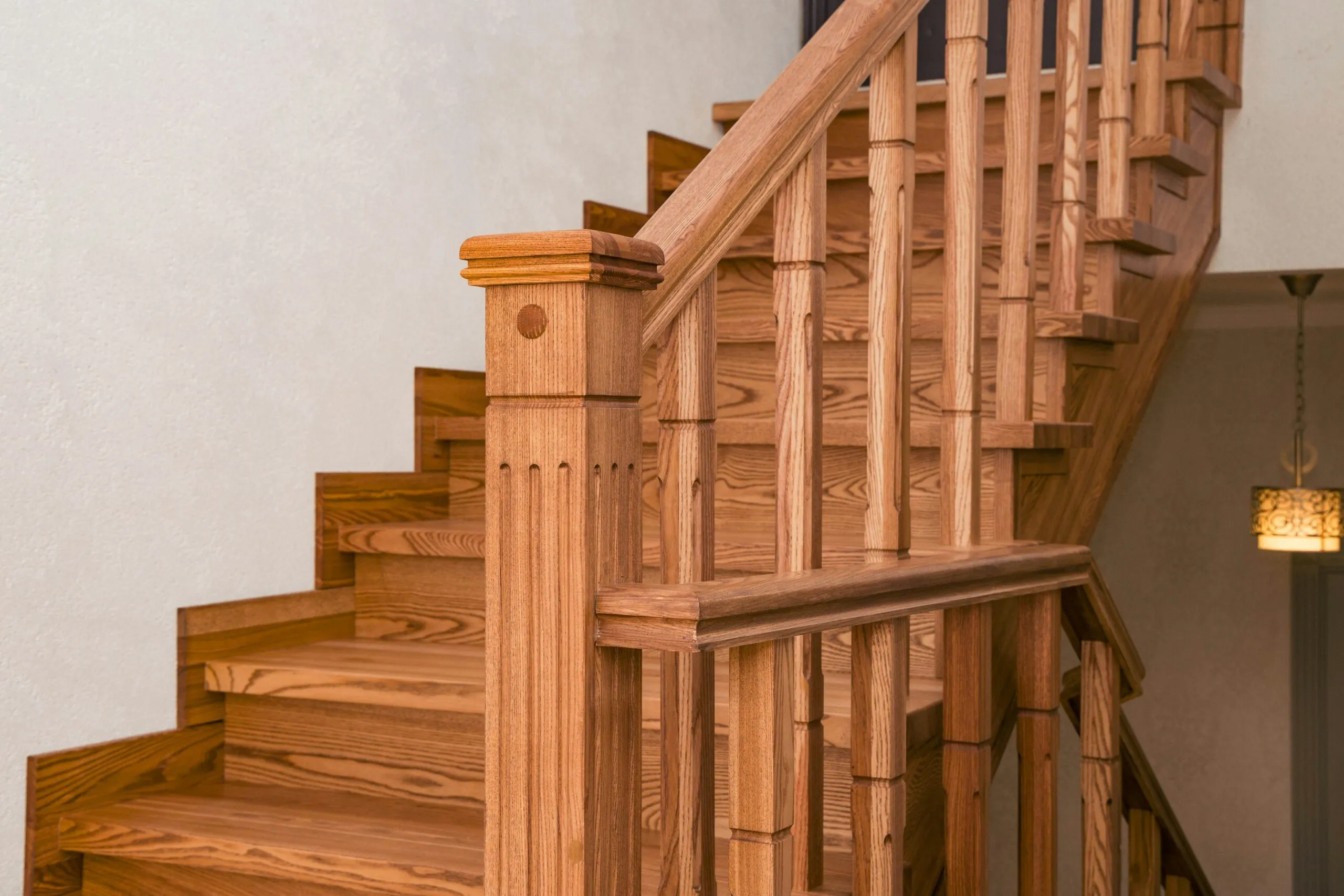 Wooden staircase with ornate balusters and newel post.