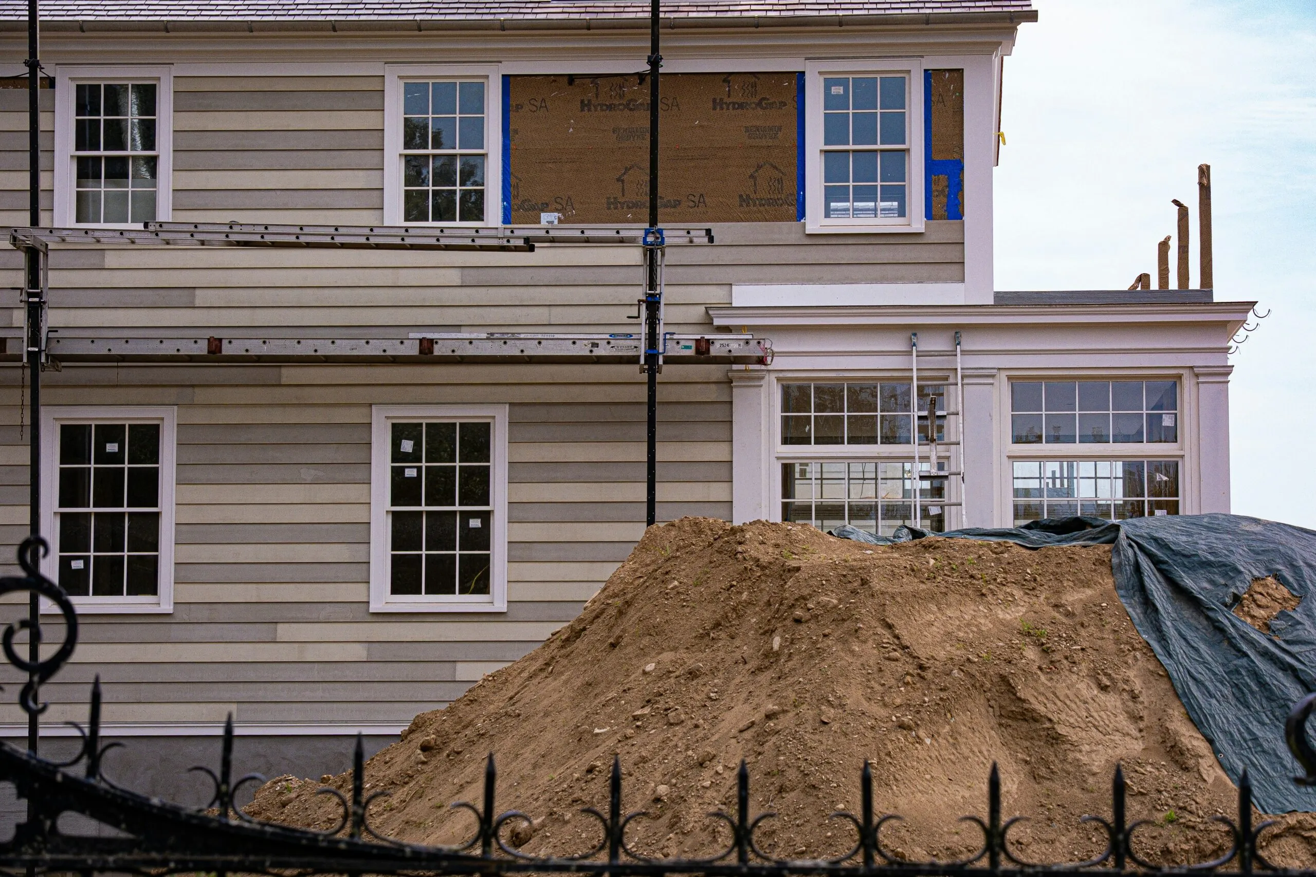 House under renovation with scaffolding and dirt pile.