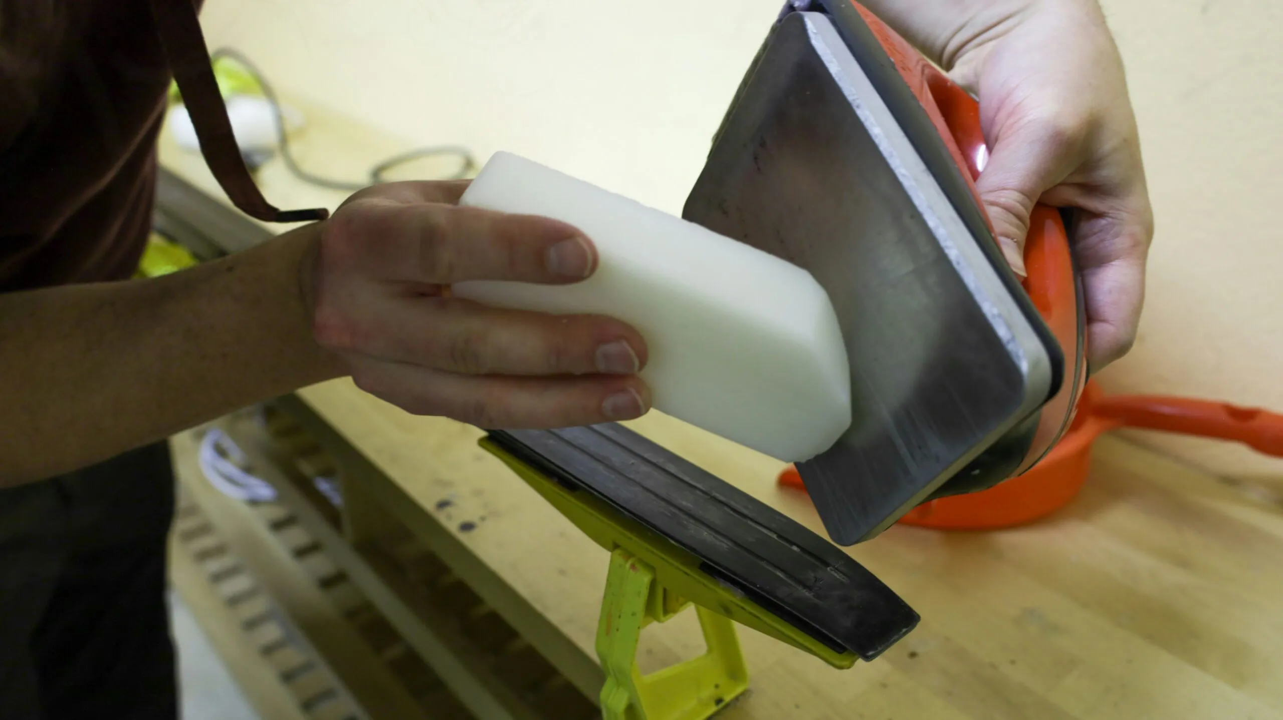 Person waxing a ski edge with a block.
