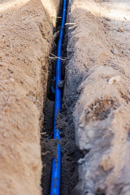 Laying a blue electrical cable in a trench in the ground. Underground communications. Electrical work at the construction site.