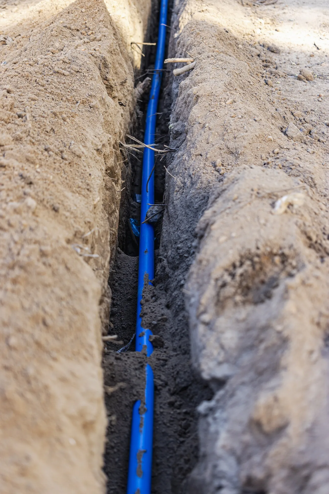 Laying a blue electrical cable in a trench in the ground. Underground communications. Electrical work at the construction site.