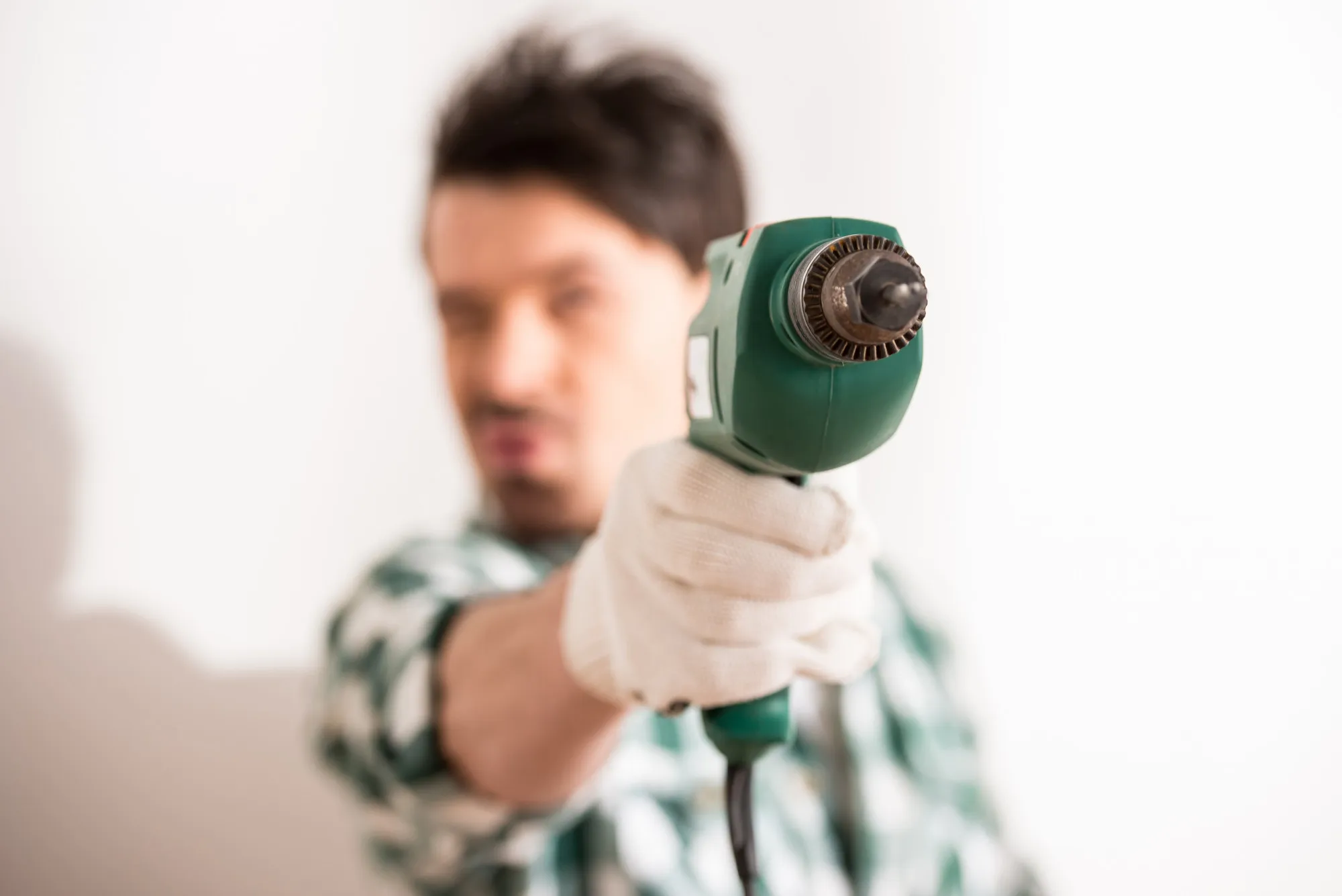 Close-up of young man is holding electric drill.