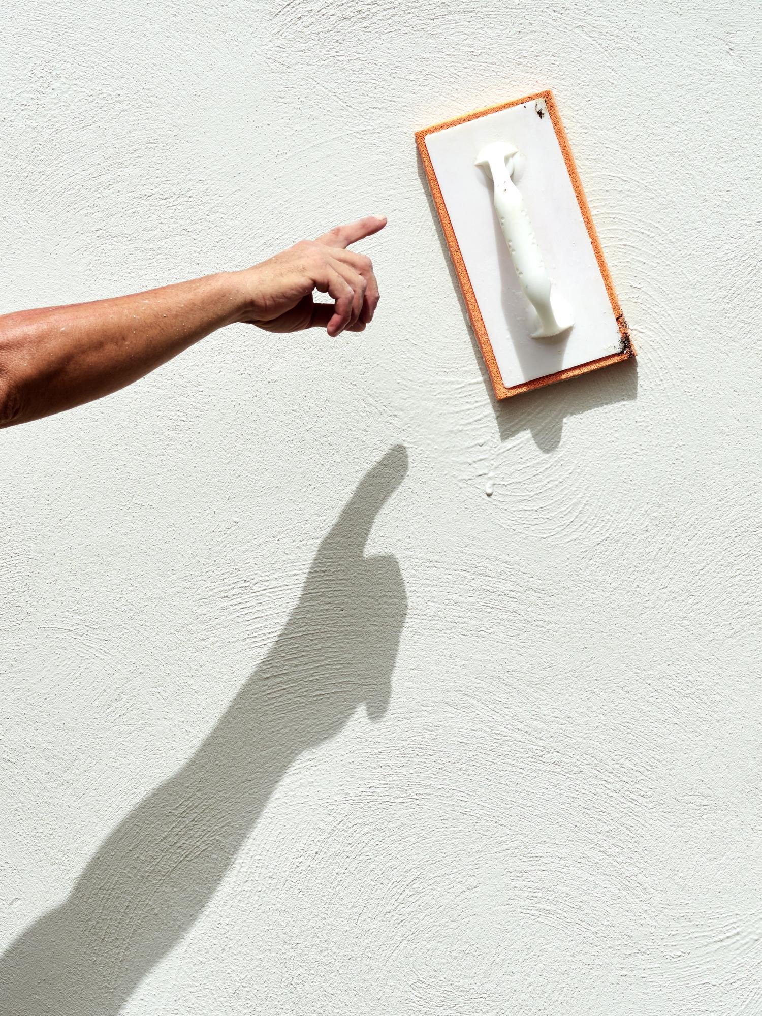 closeup hand of worker plastering white cement at wall for building house