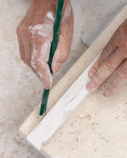 Craftsman with dirty hands drawing a line on marble with a pencil Construction or renovation