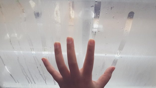 Cropped hand on condensed window in bathroom