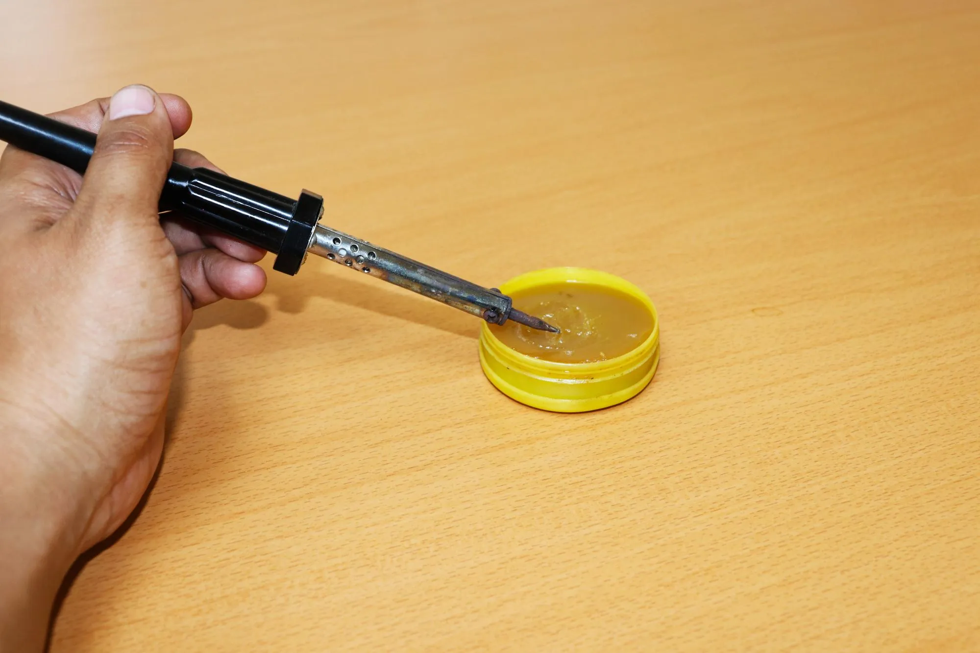 Cropped hand holding soldering iron