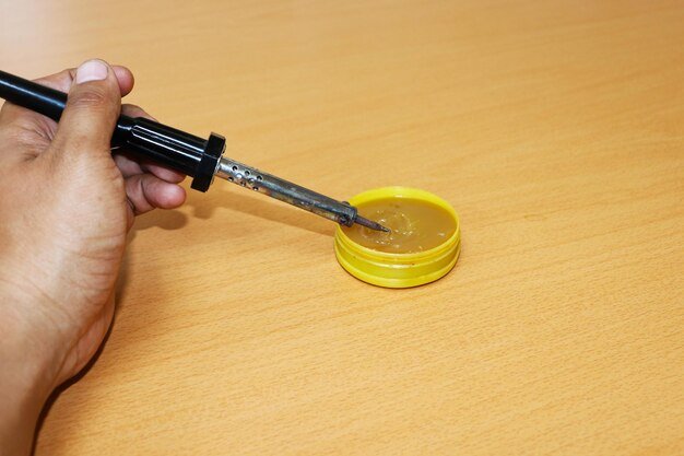 Cropped hand holding soldering iron
