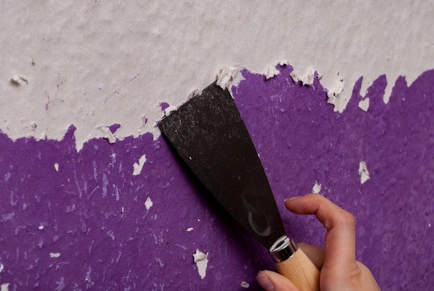 Cropped hand of man peeling paint on wall