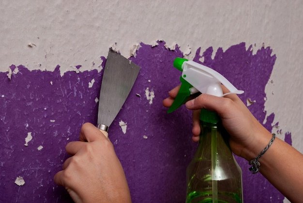 Cropped hand of man peeling paint on wall