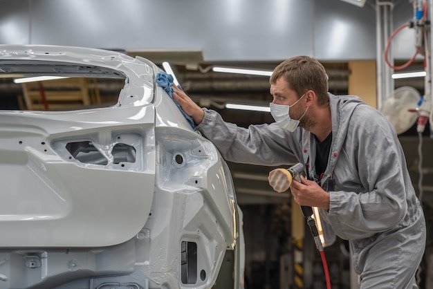 An employee of the paint shop of an automobile plant polishes the painted surface
