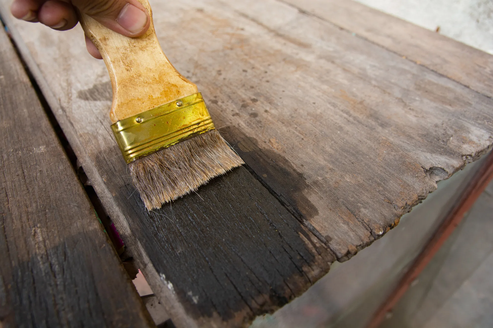 Hand holding a brush Painting wooden timber boards surface with Wood Stain