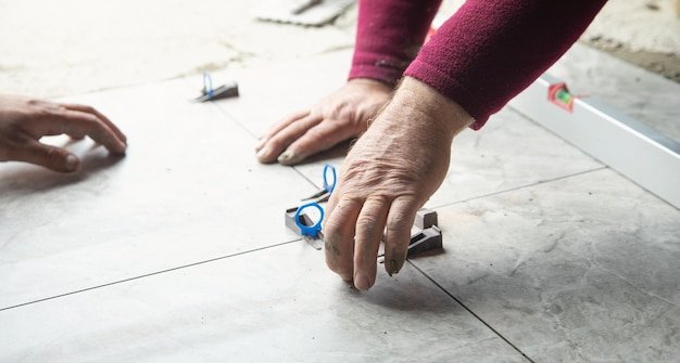 Hand places a plastic clip between the tile