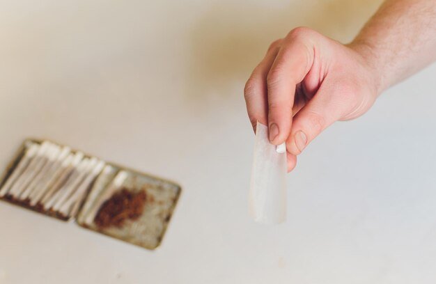 Hands Rolling a Cigarette Paper with Tobacco