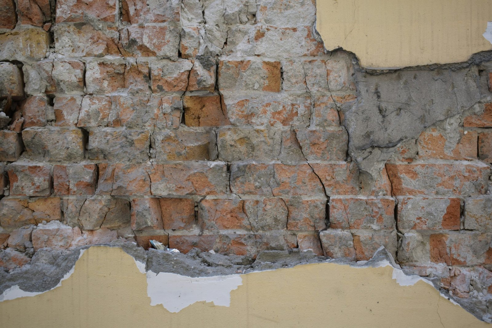Damaged brick wall with peeling plaster
