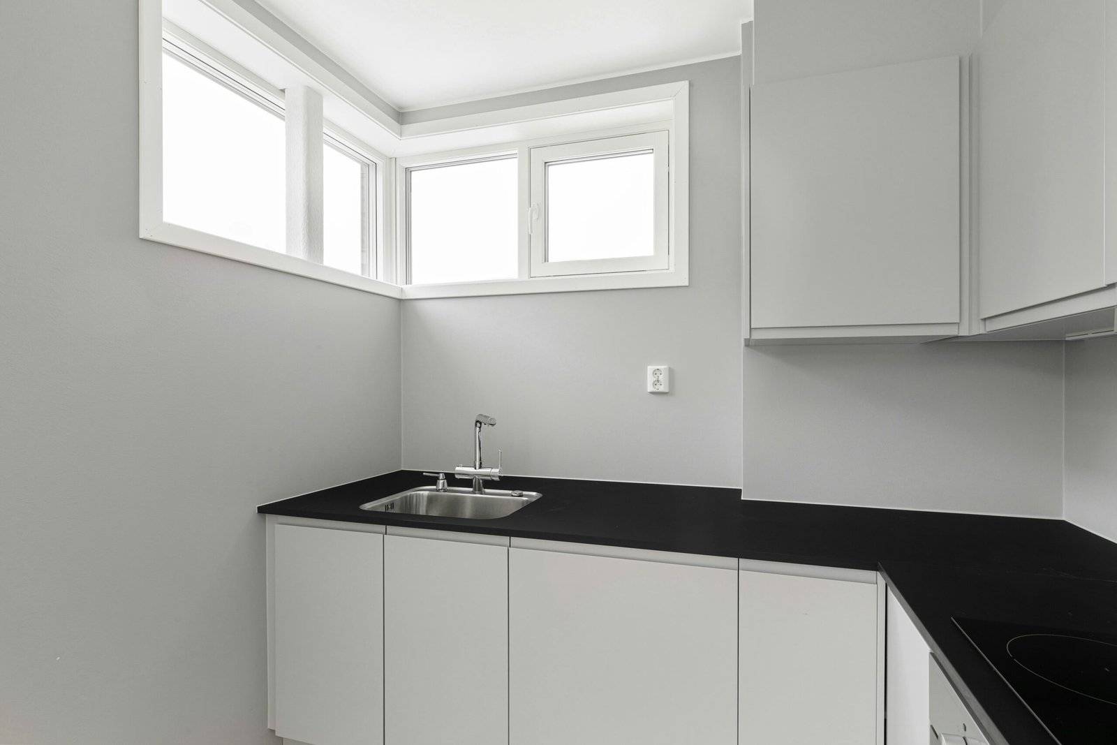 A kitchen with white cabinets and black counter tops