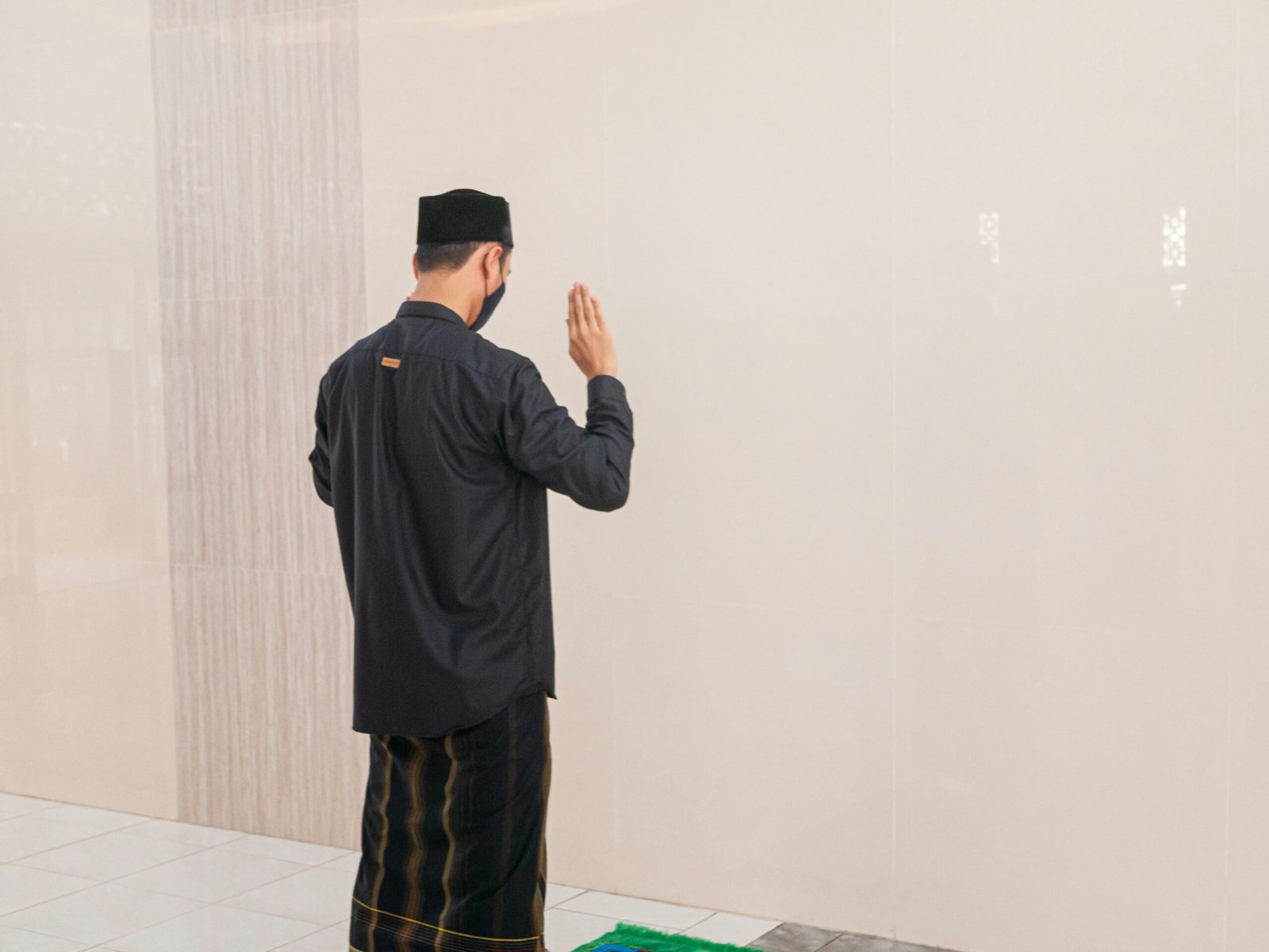 man in black jacket standing near white wall