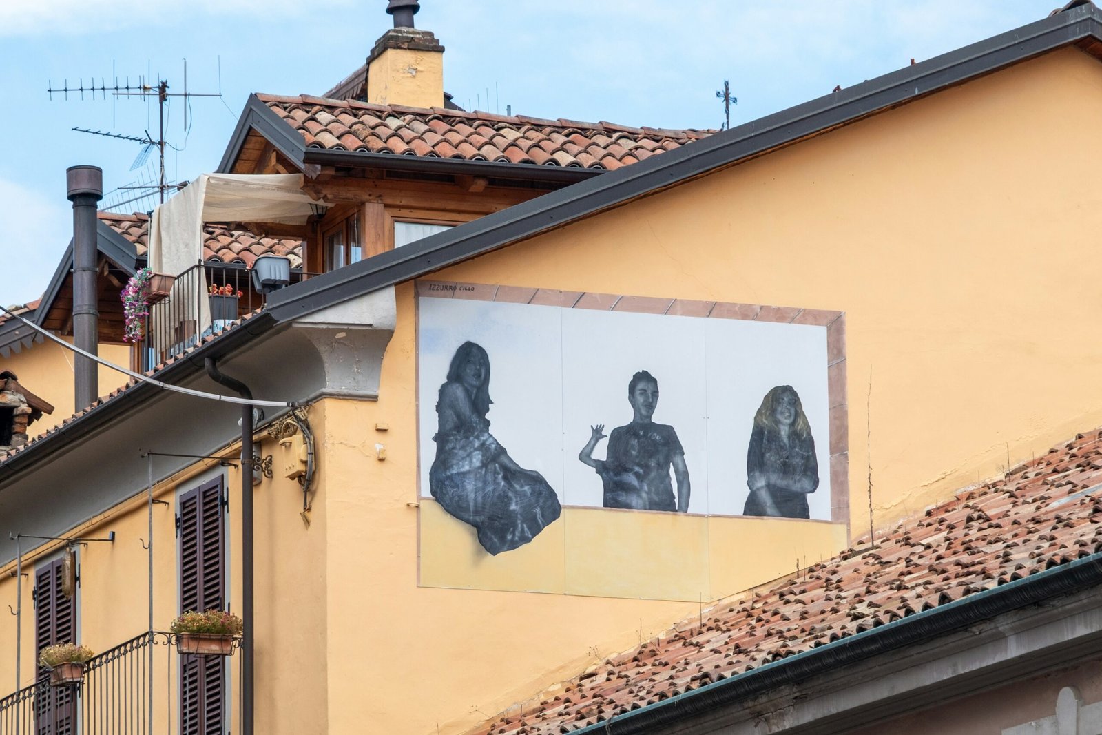 Mural of three figures on a yellow building wall.
