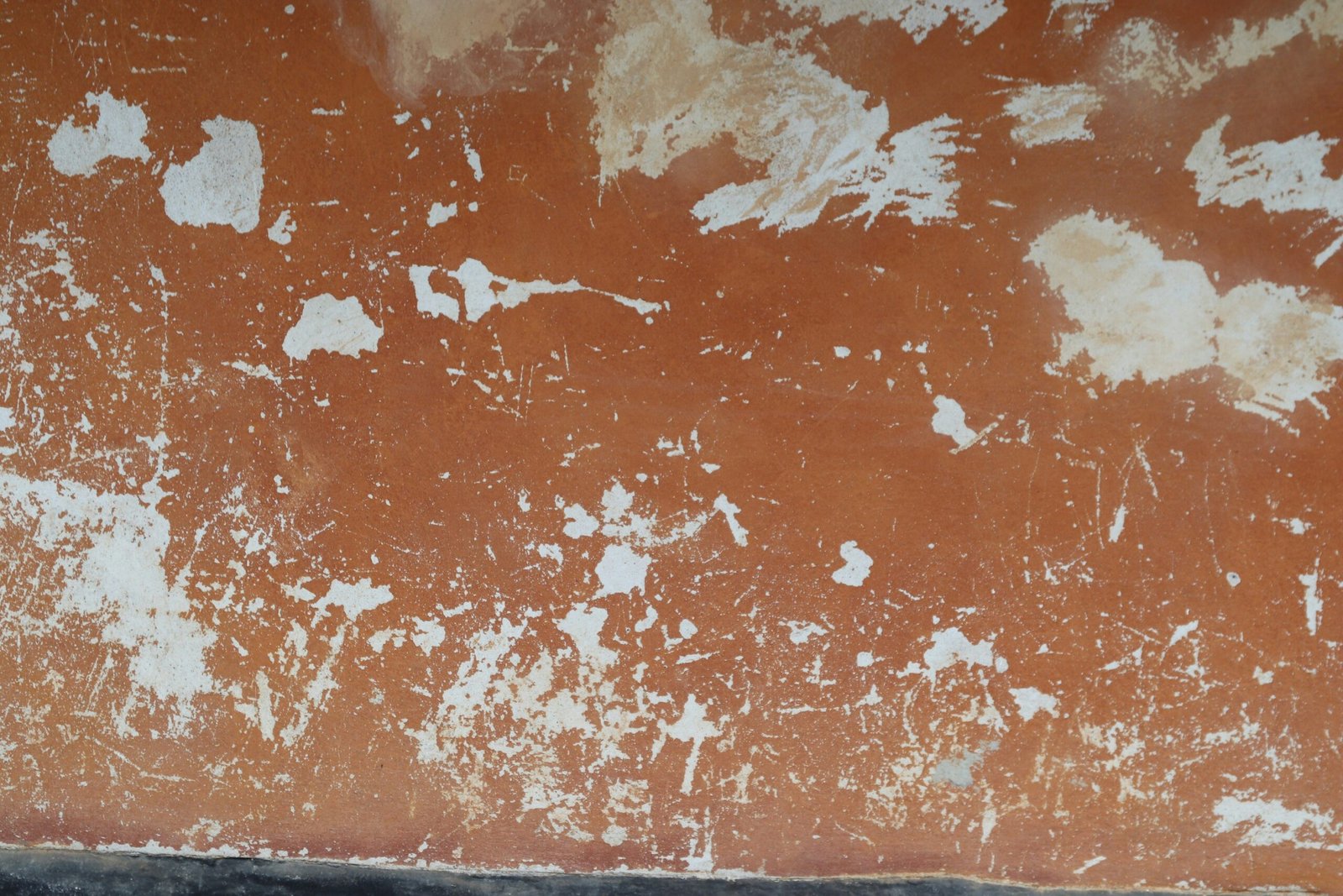 Orange wall with chipped paint and scratches.