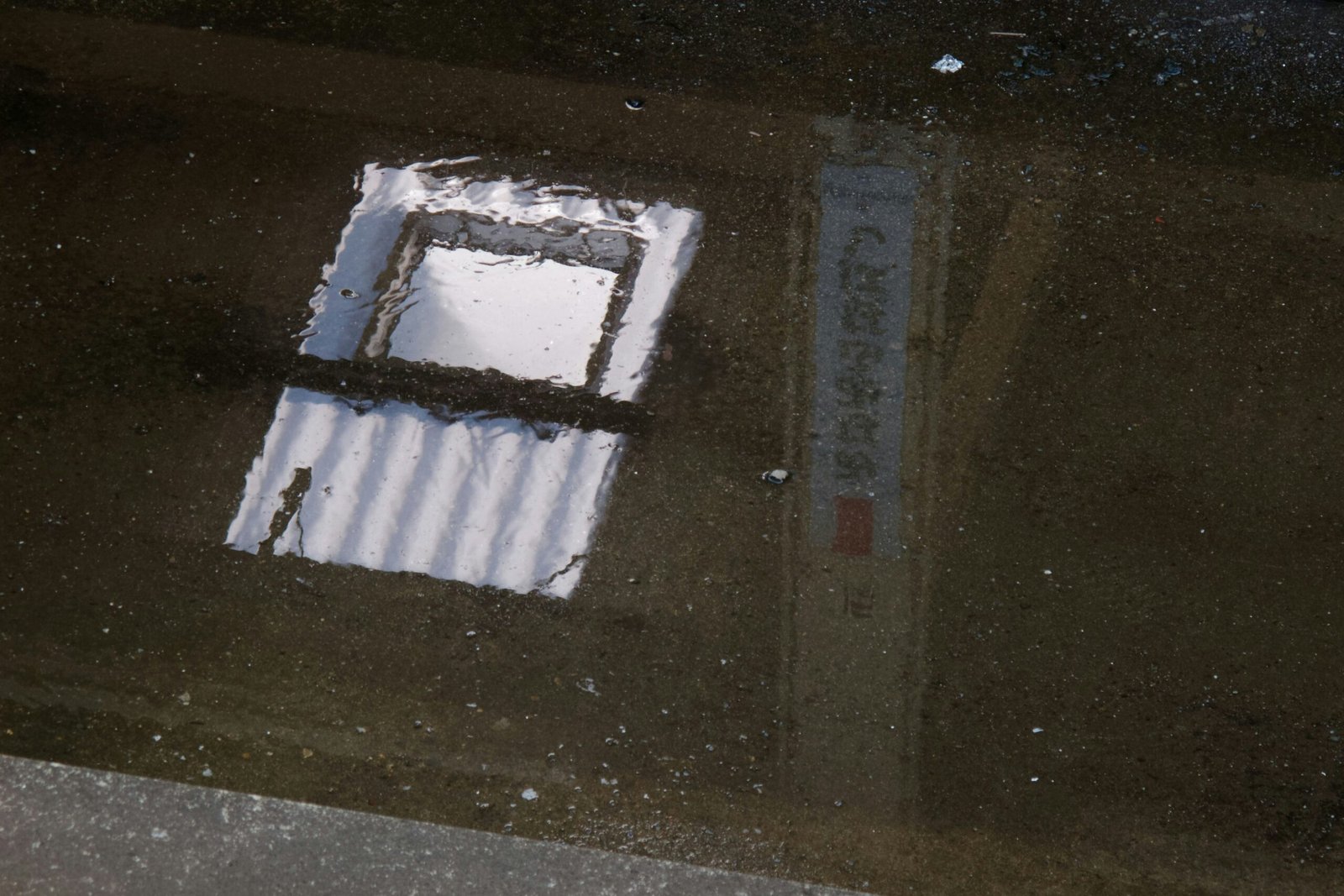 a reflection of a window in a puddle of water
