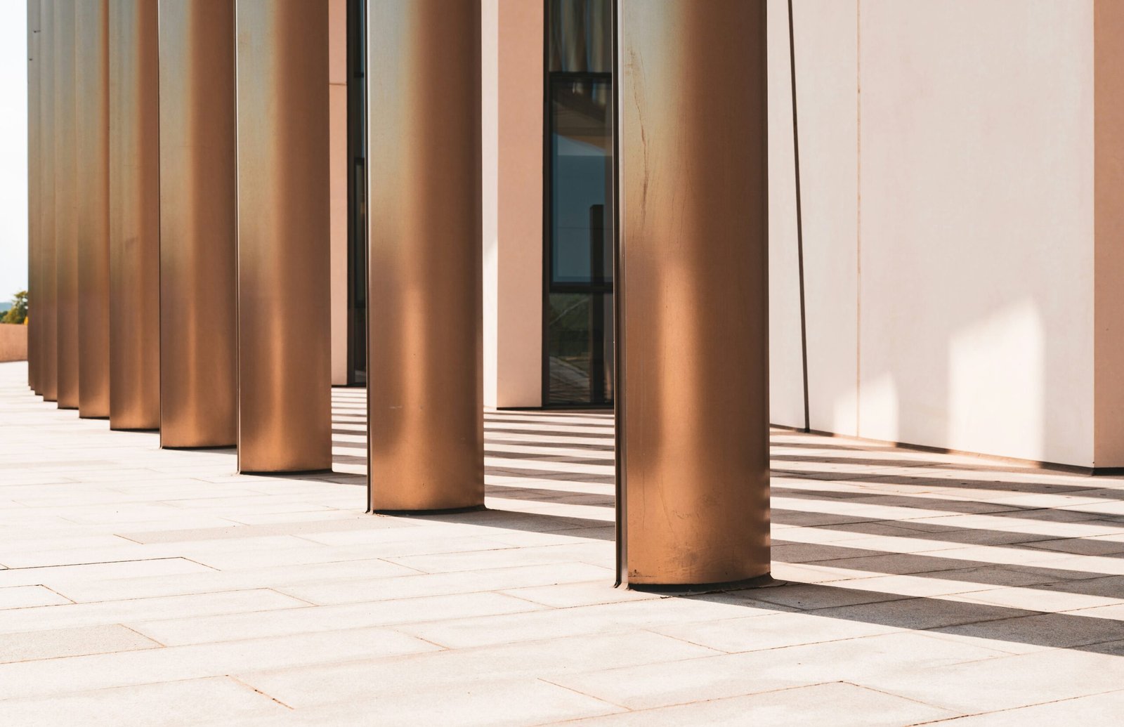 Row of copper-colored columns casting long shadows