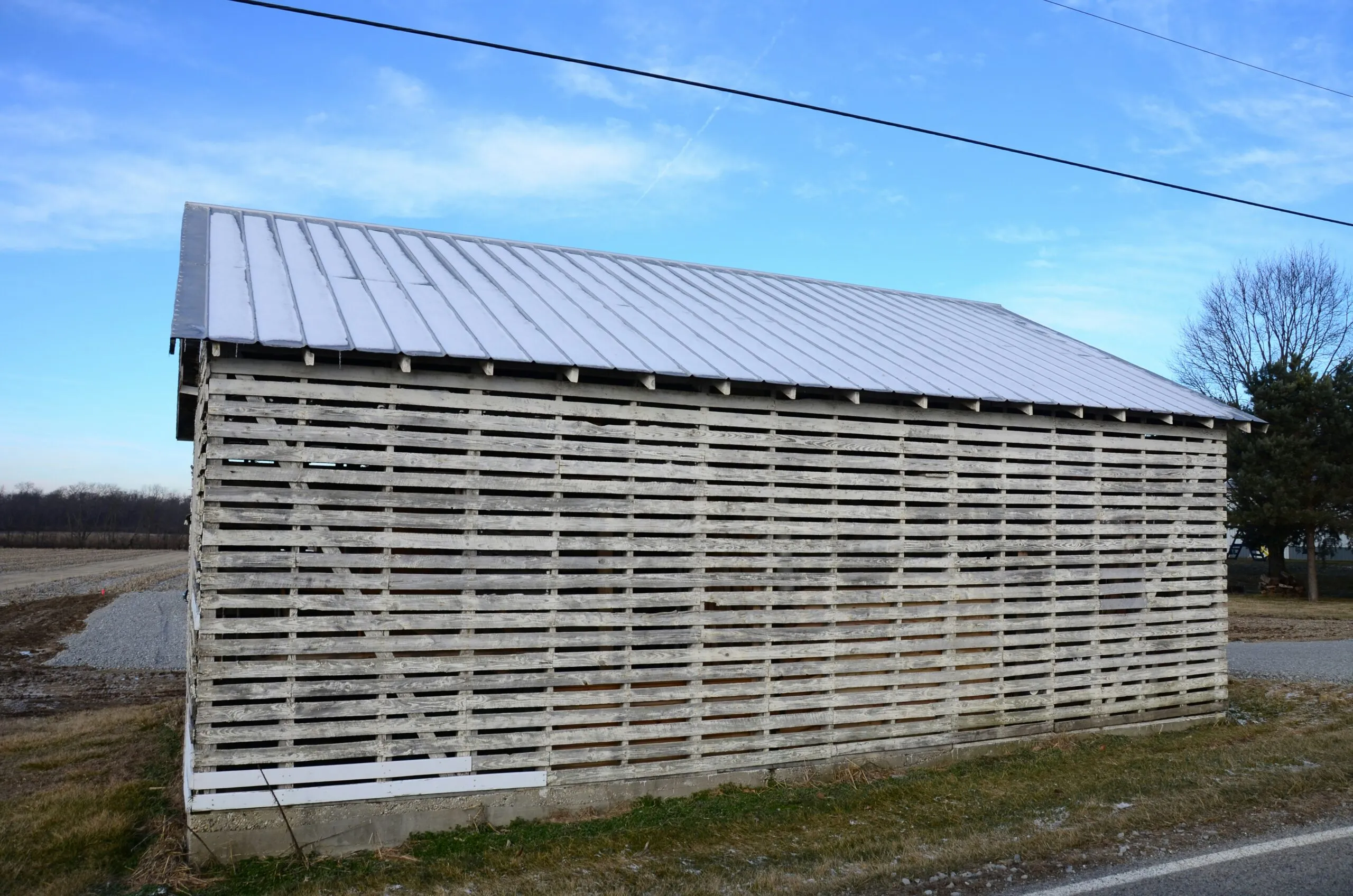a wooden building with a metal roof next to a road