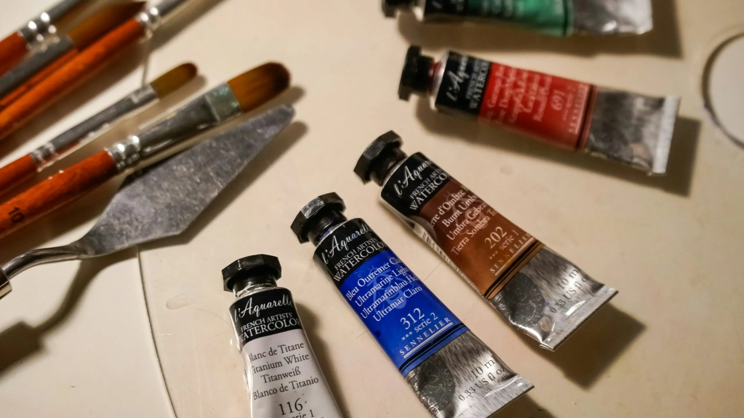 Artist's paint tubes and brushes on a surface.