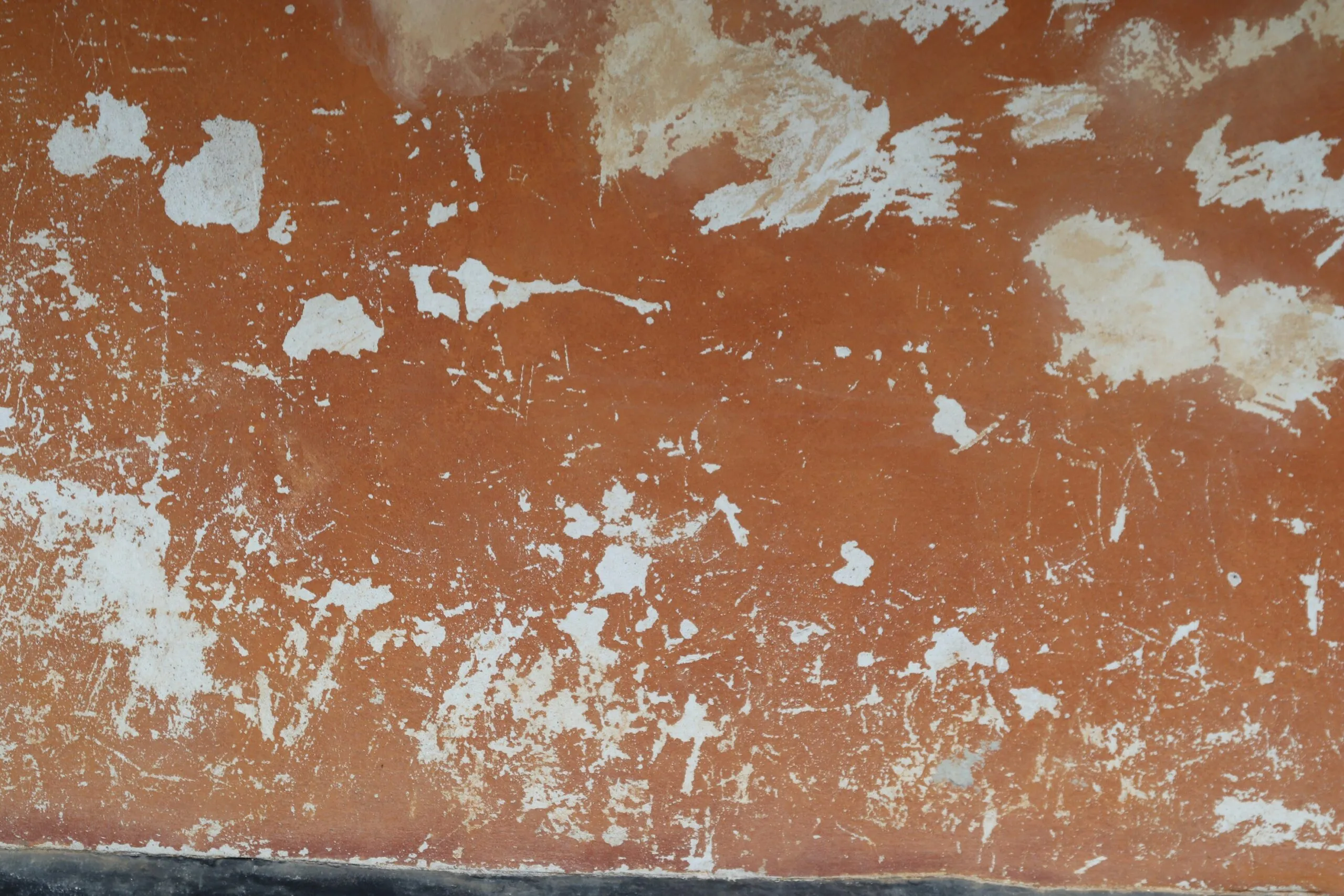 Orange wall with chipped paint and scratches.