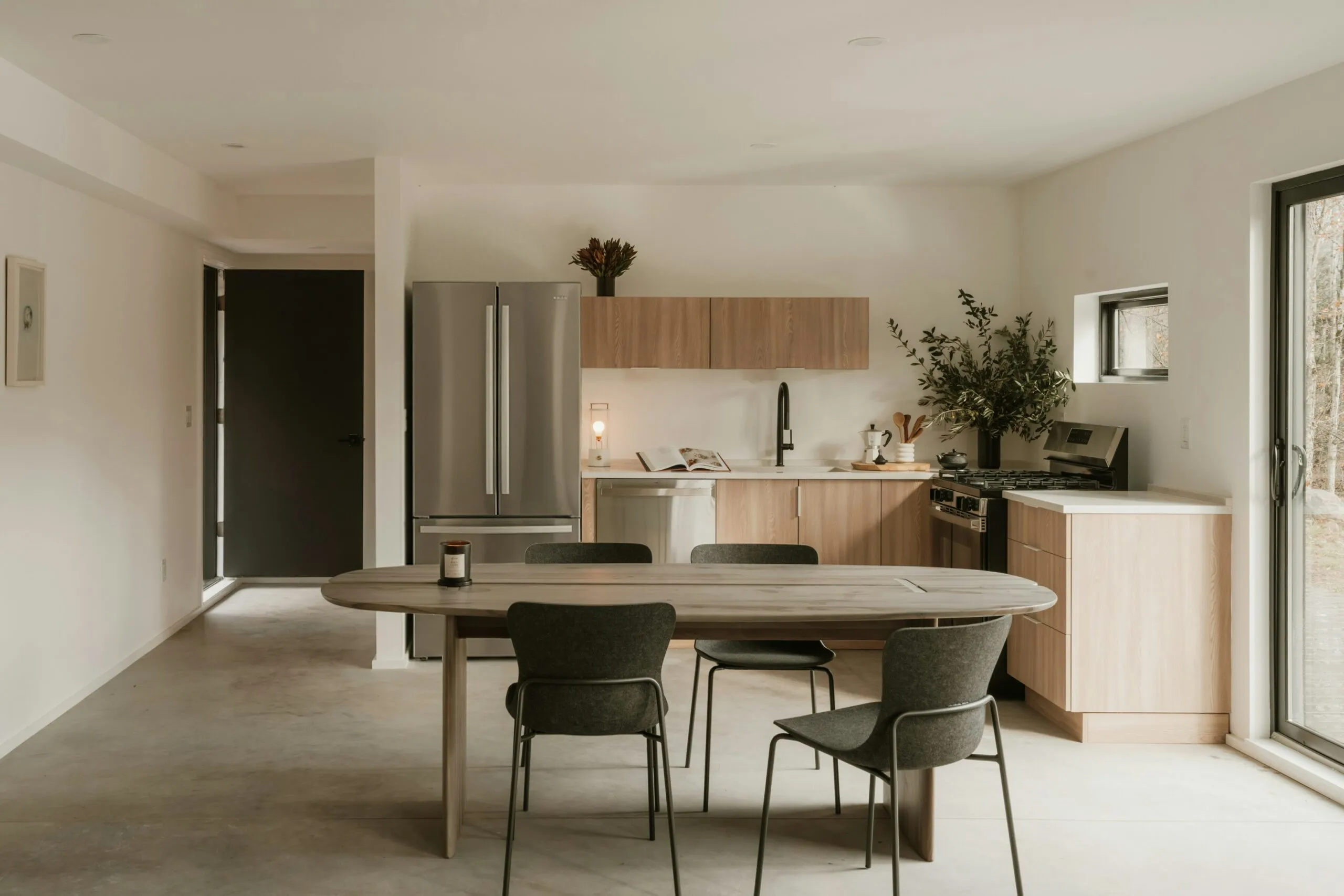 Modern kitchen and dining area with wooden table.