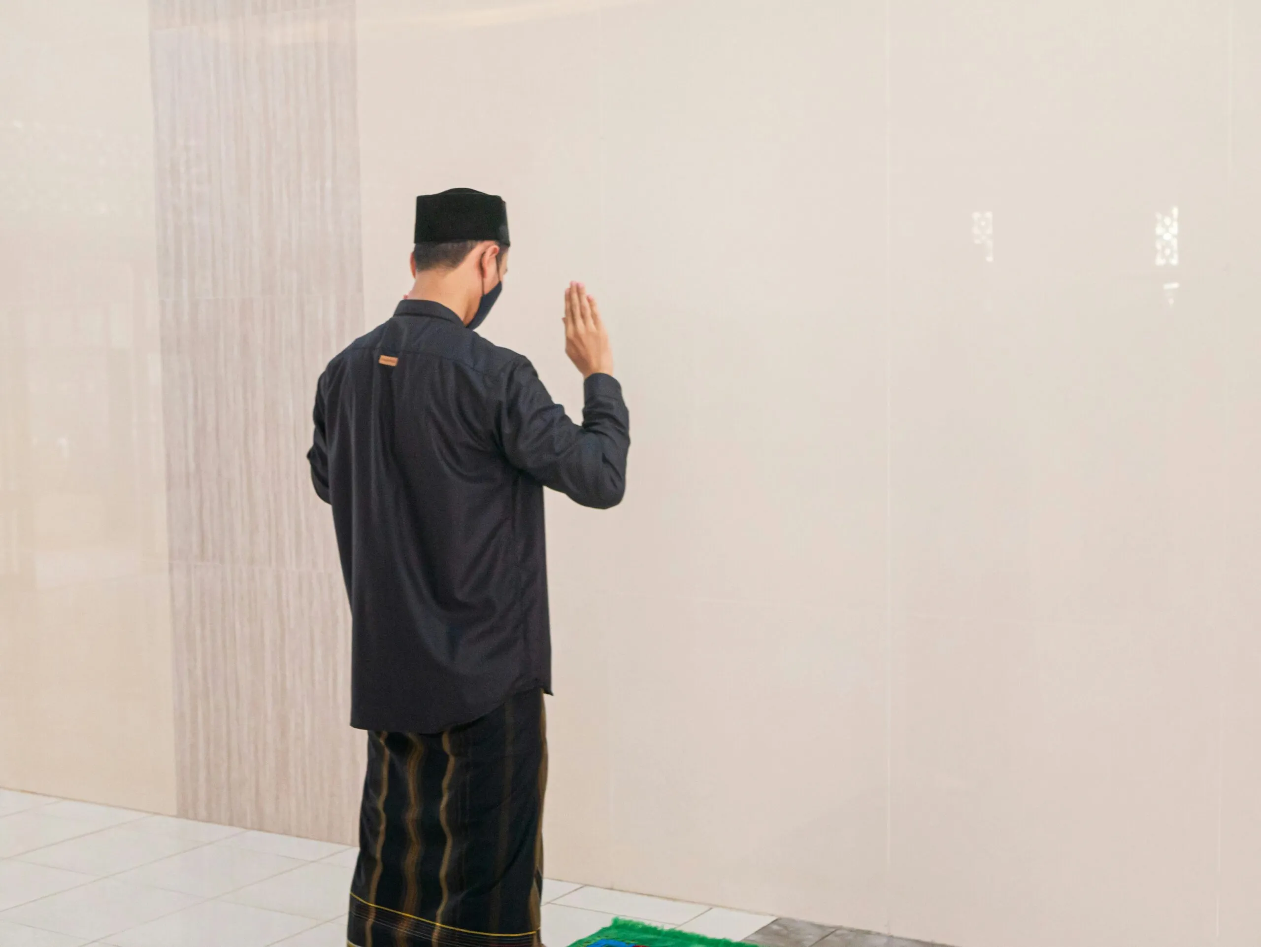 man in black jacket standing near white wall