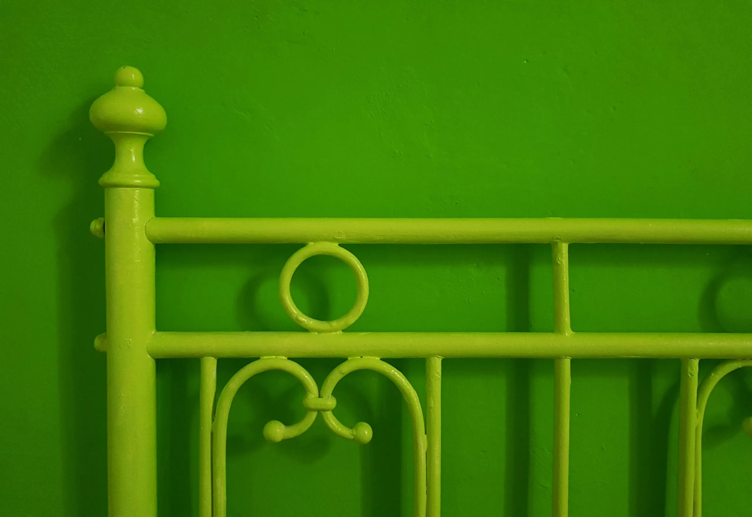 a green metal bed frame against a green wall