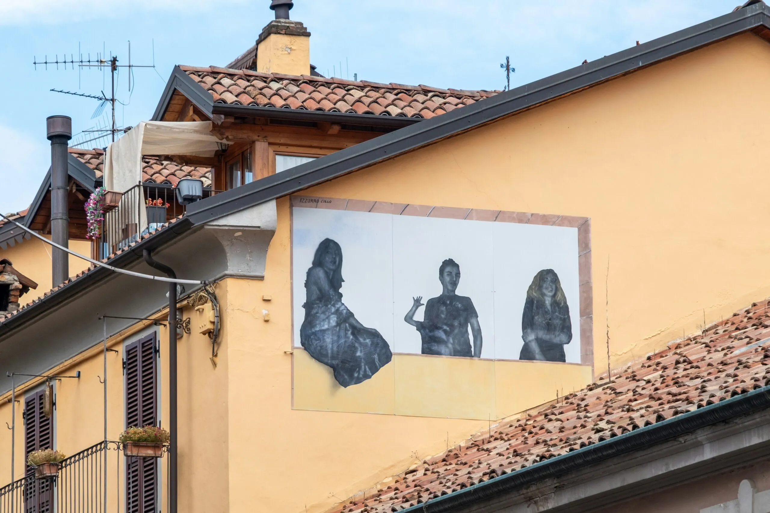 Mural of three figures on a yellow building wall.