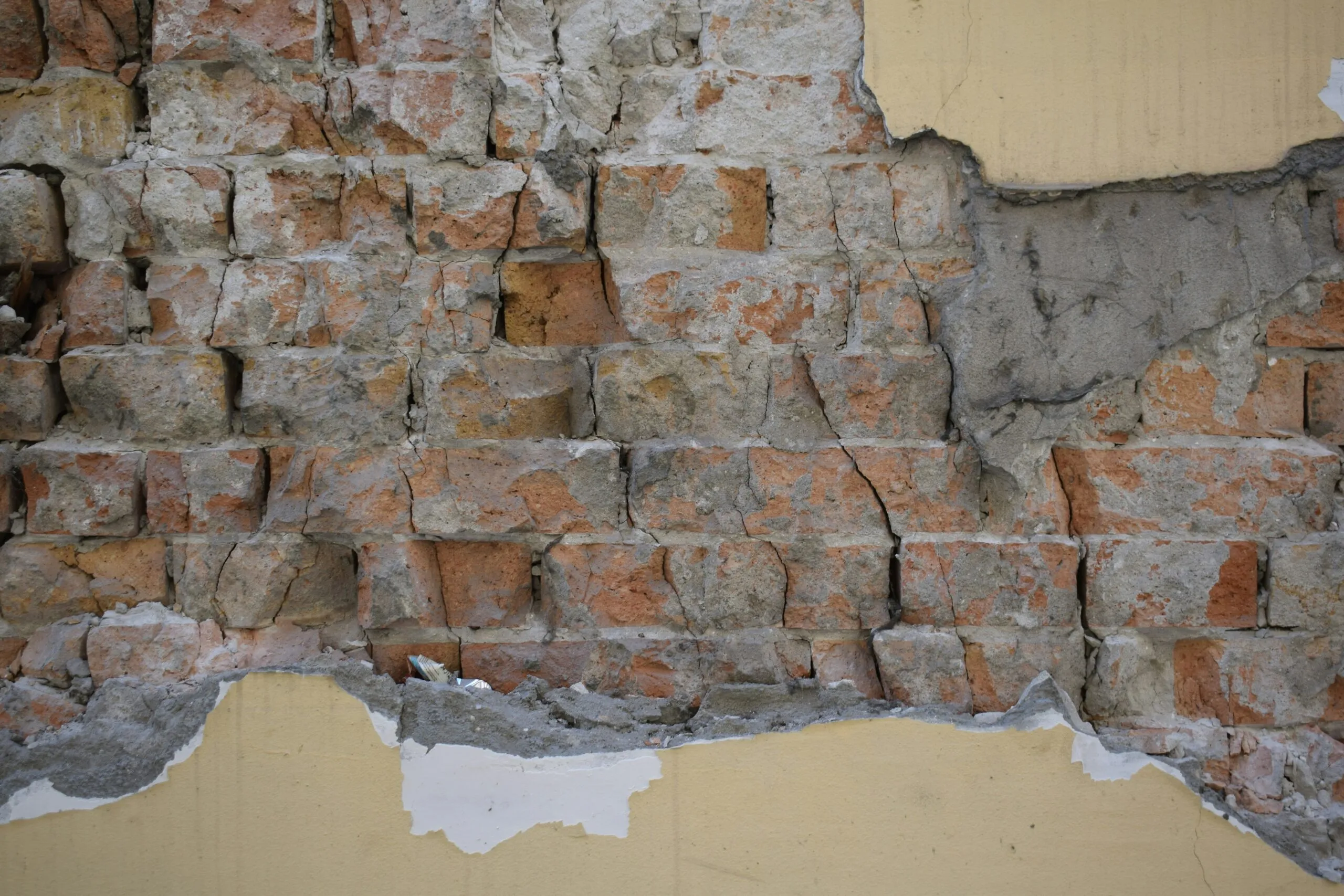 Damaged brick wall with peeling plaster