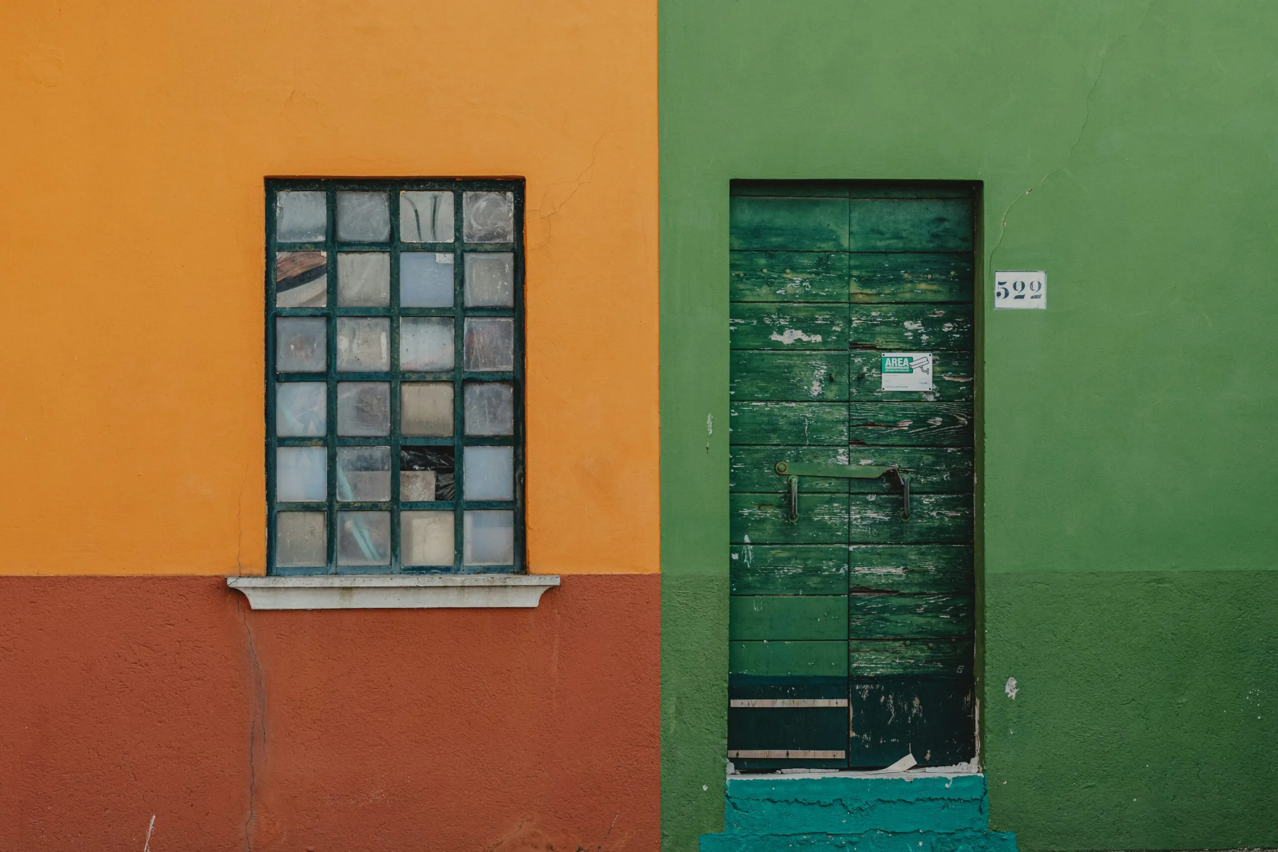 Orange and green wall with a window and door.