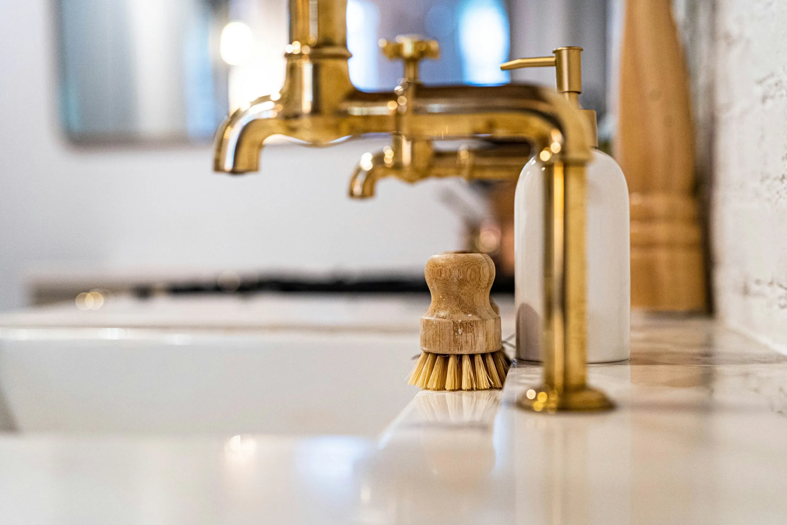 a bathroom sink with a gold faucet next to it
