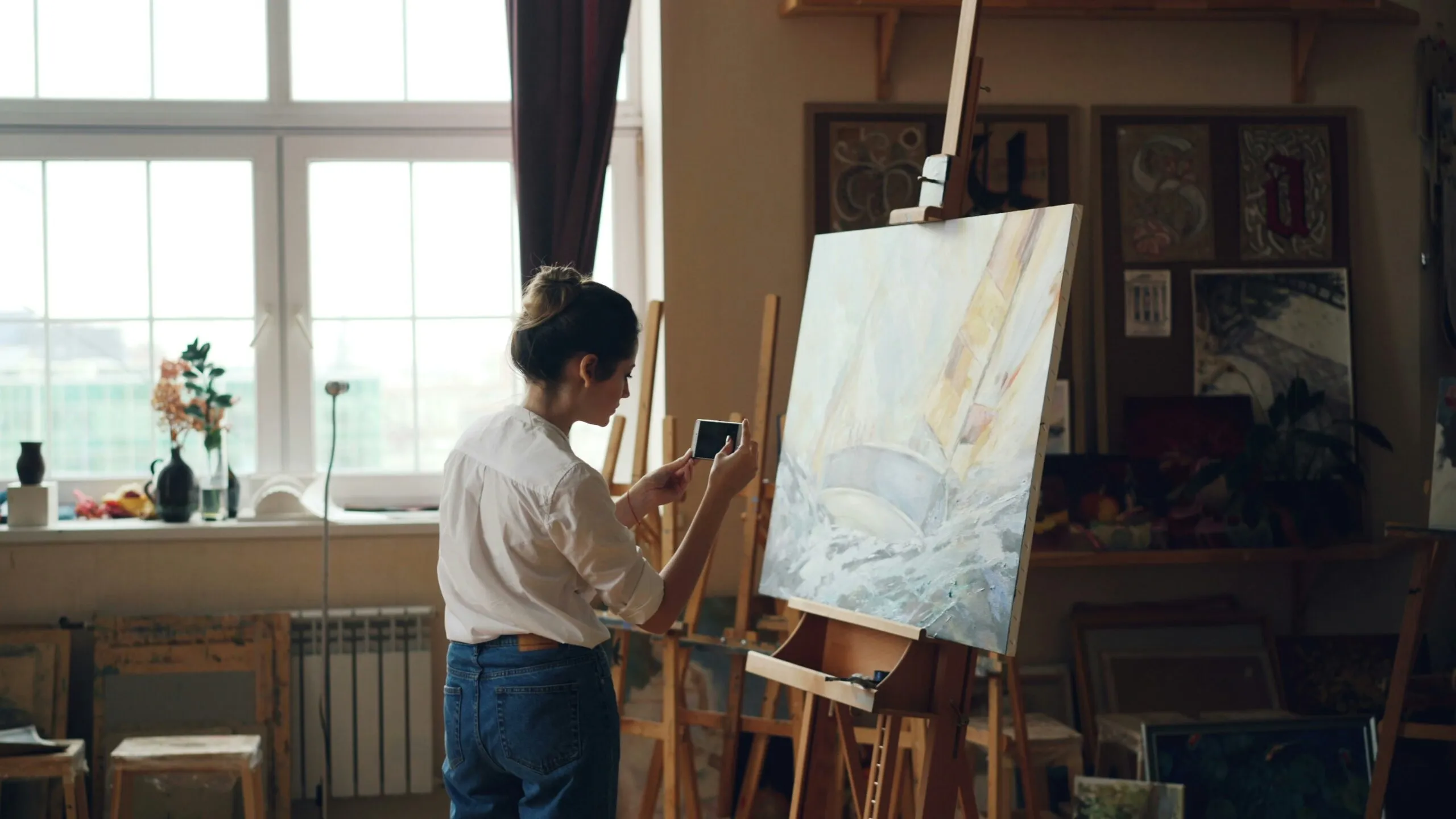 An artist photographs her painting in a sunny studio.
