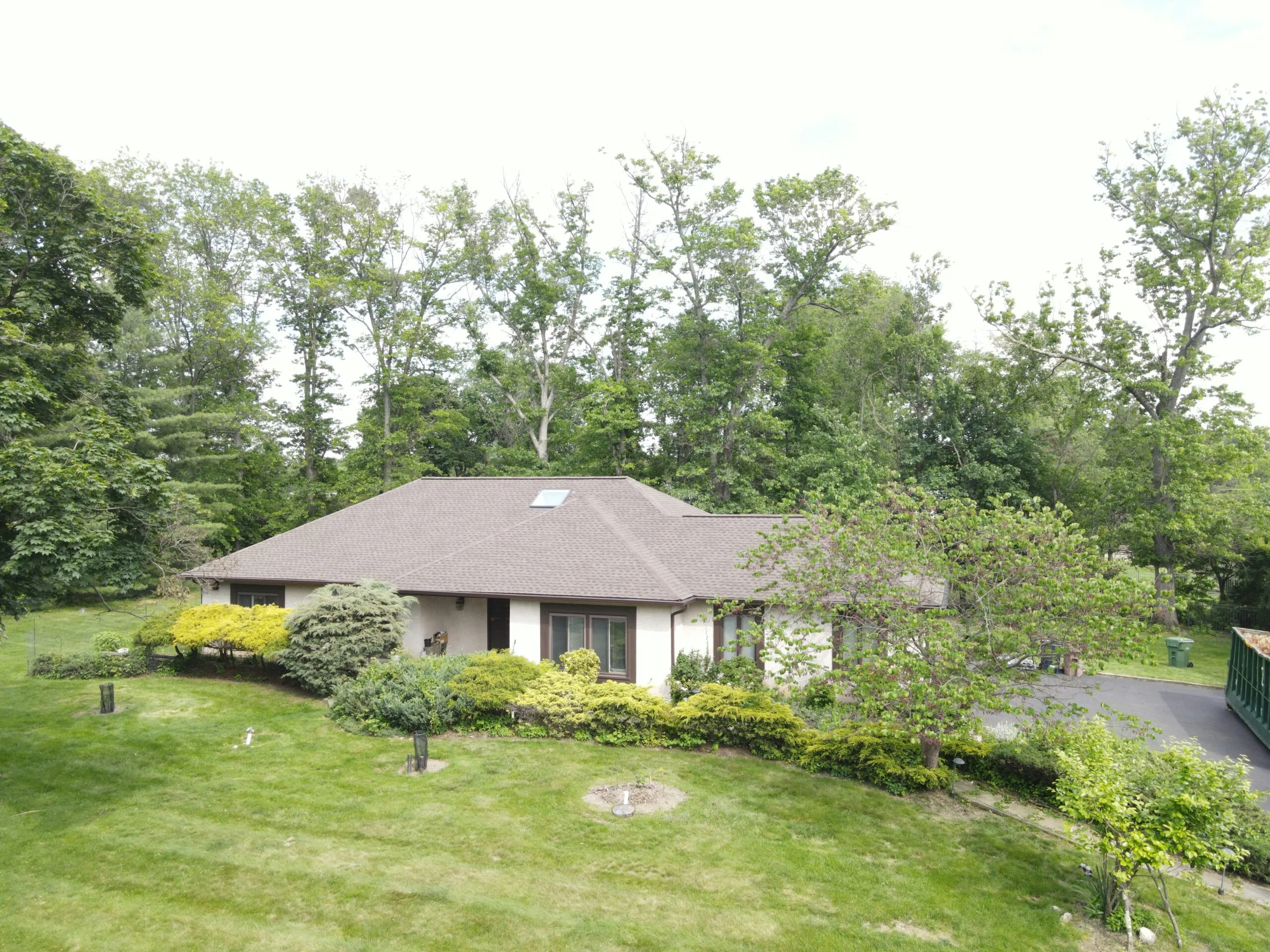 A suburban house nestled among trees on a grassy hill.