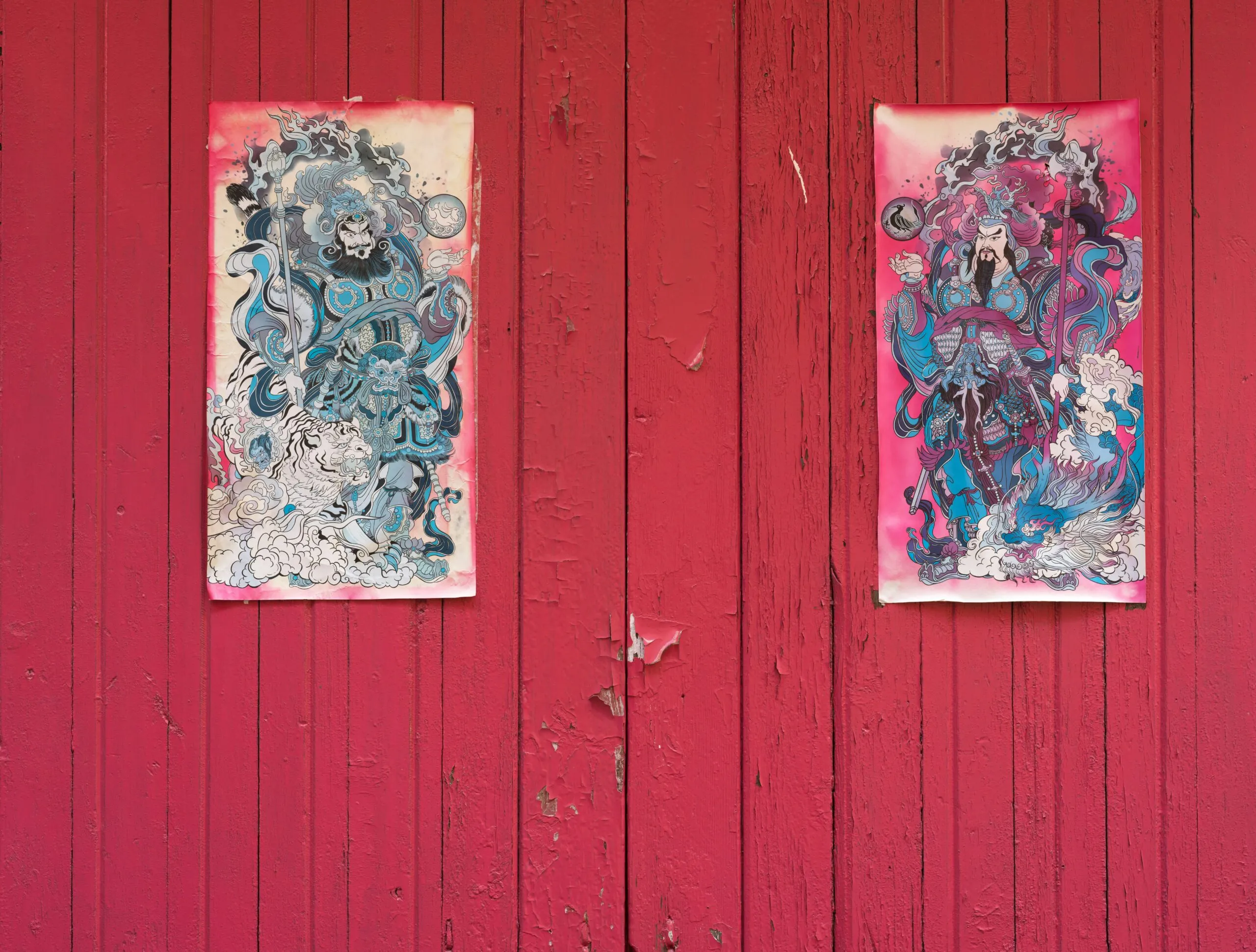 Two paintings are hanging on a red wall