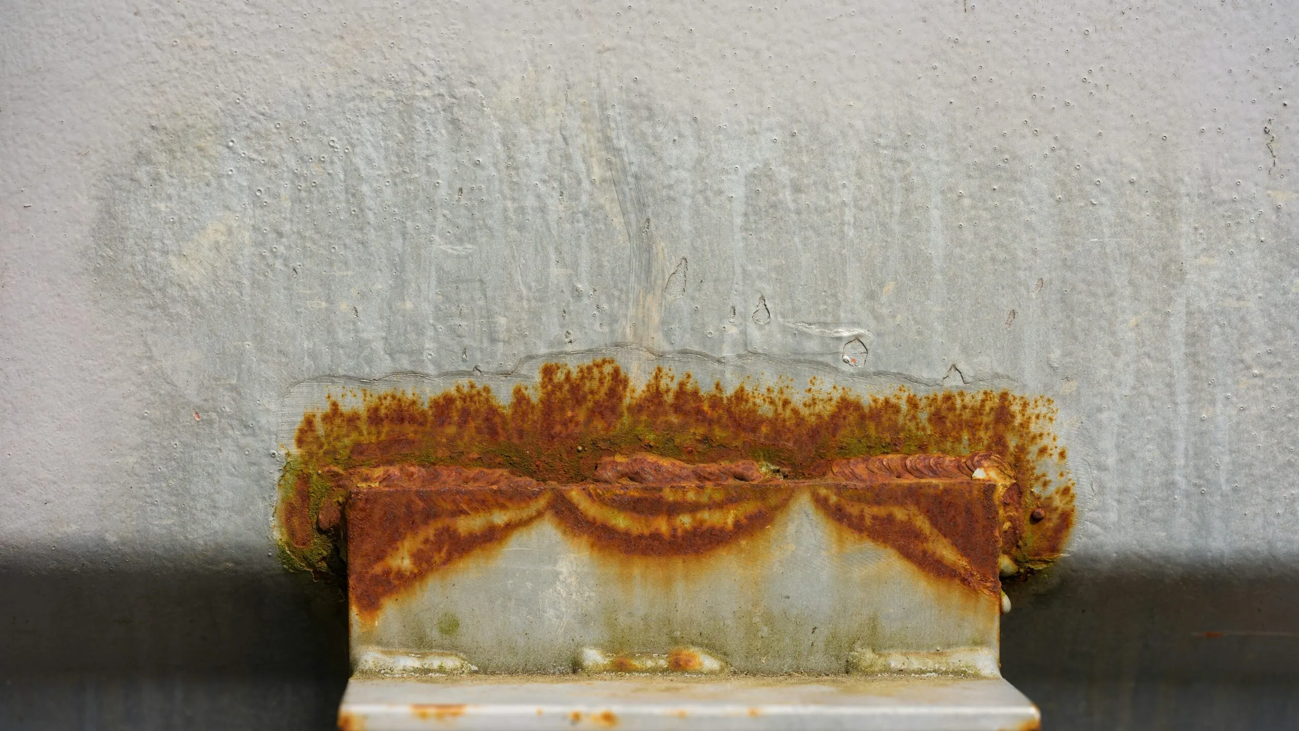 Rust stains a metal bracket attached to a wall.