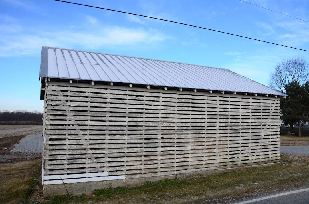 a wooden building with a metal roof next to a road