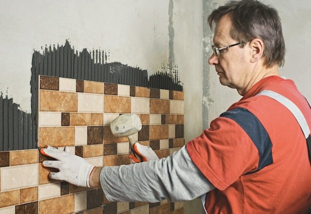 Laying Ceramic Tiles. Tiler knocking on the tiles with a rubber mallet