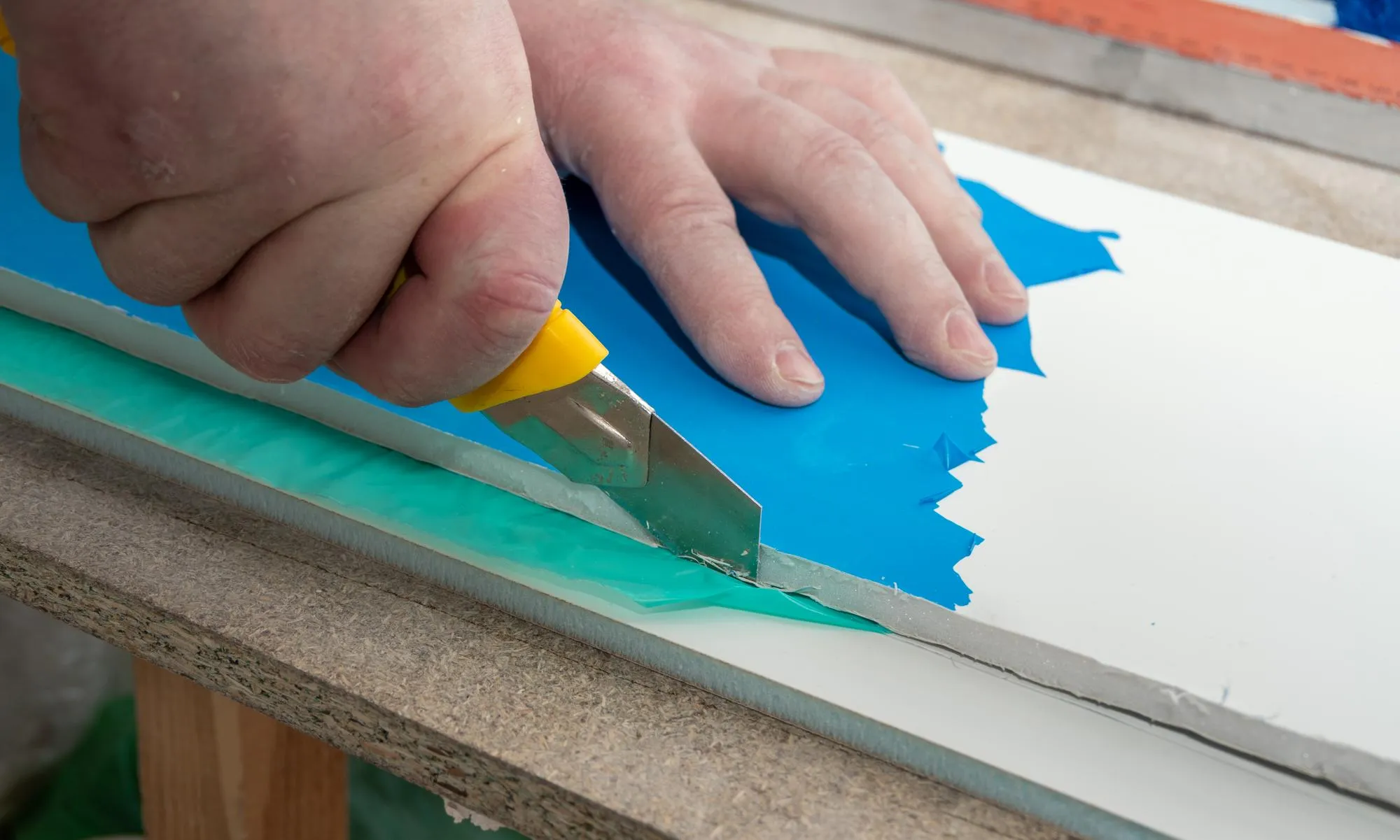 Male hands cut drywall sandwich panel with a construction knife Repair of a house or apartment Slope installation DIY repair