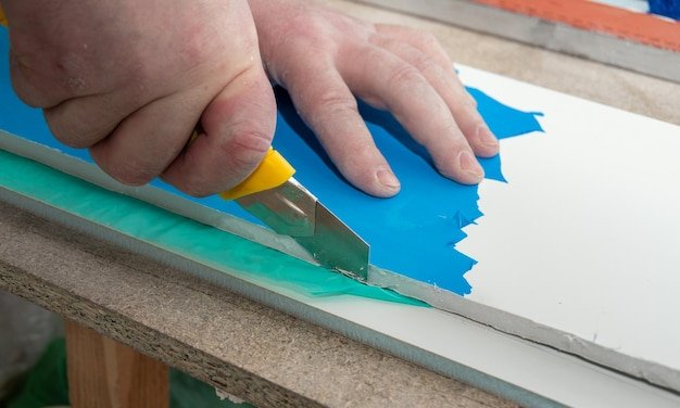 Male hands cut drywall sandwich panel with a construction knife Repair of a house or apartment Slope installation DIY repair