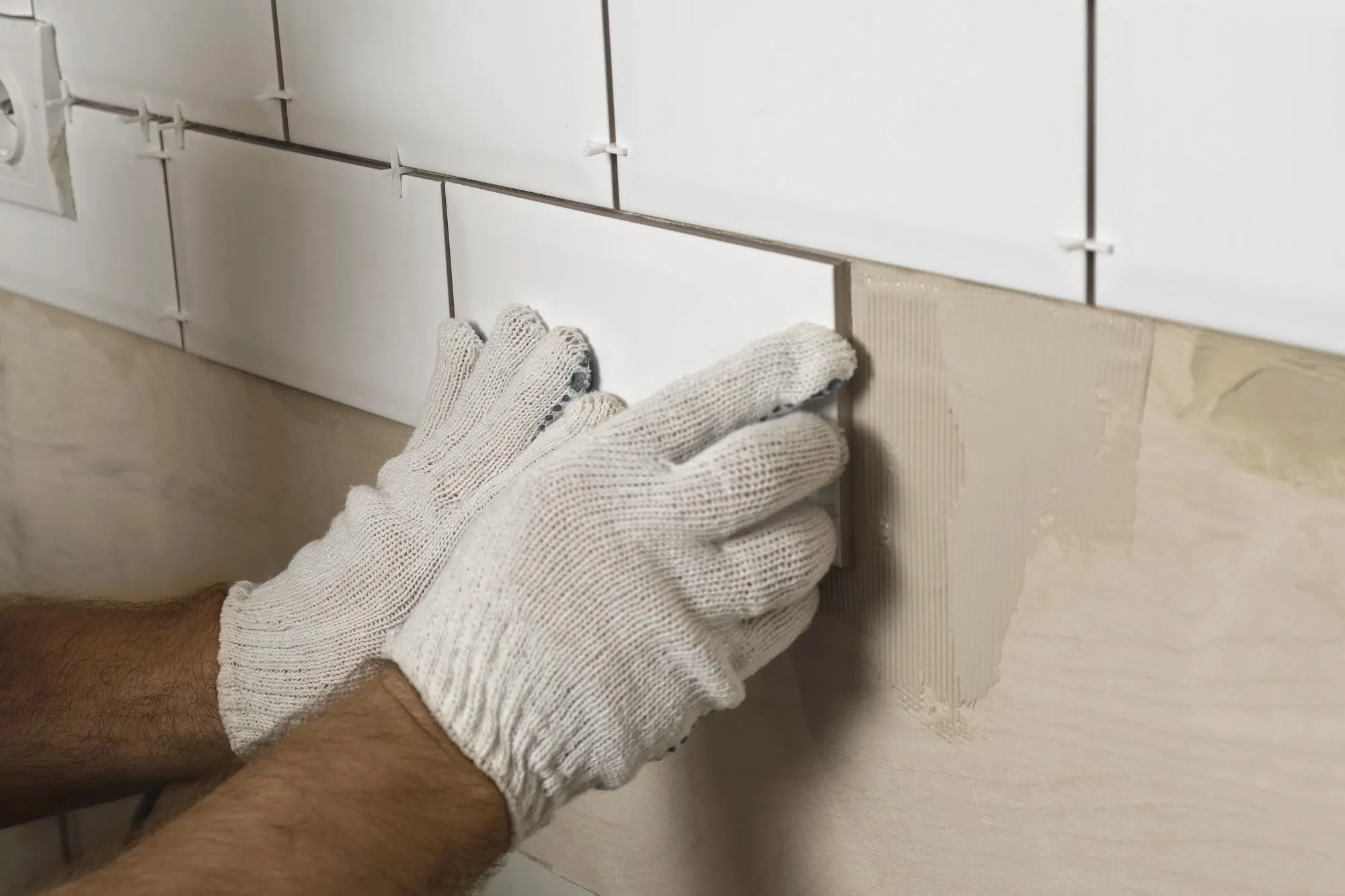 Male Worker Master Laying Ceramic Tiles on the Wall of Kitchen Repairman Placing White Modern Tiles Spreading Adhesive Builder Installing Tile at Repair Renovation Work Professional Tiling 4K