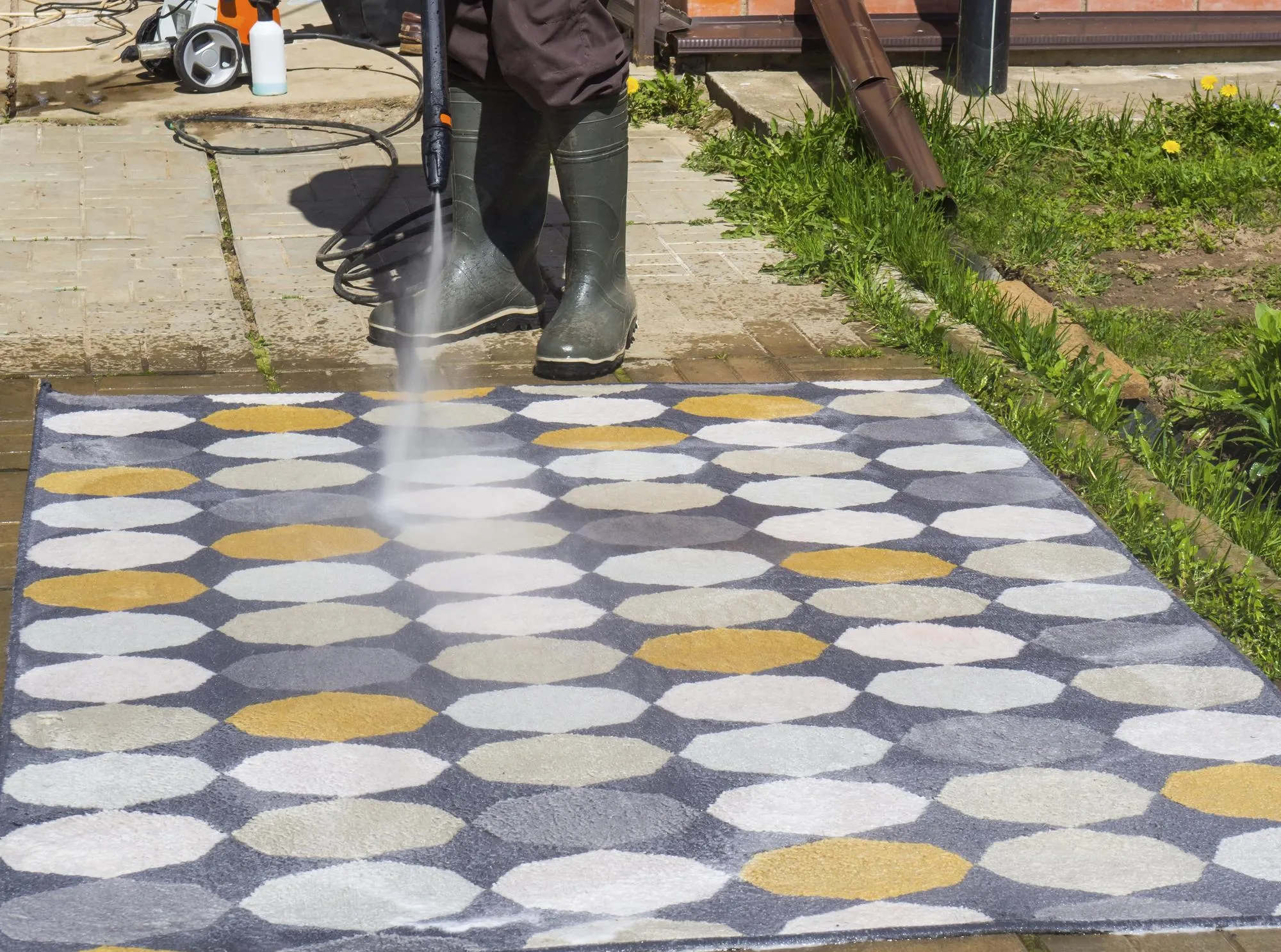 Man washing carpet with pressure washer outdoors