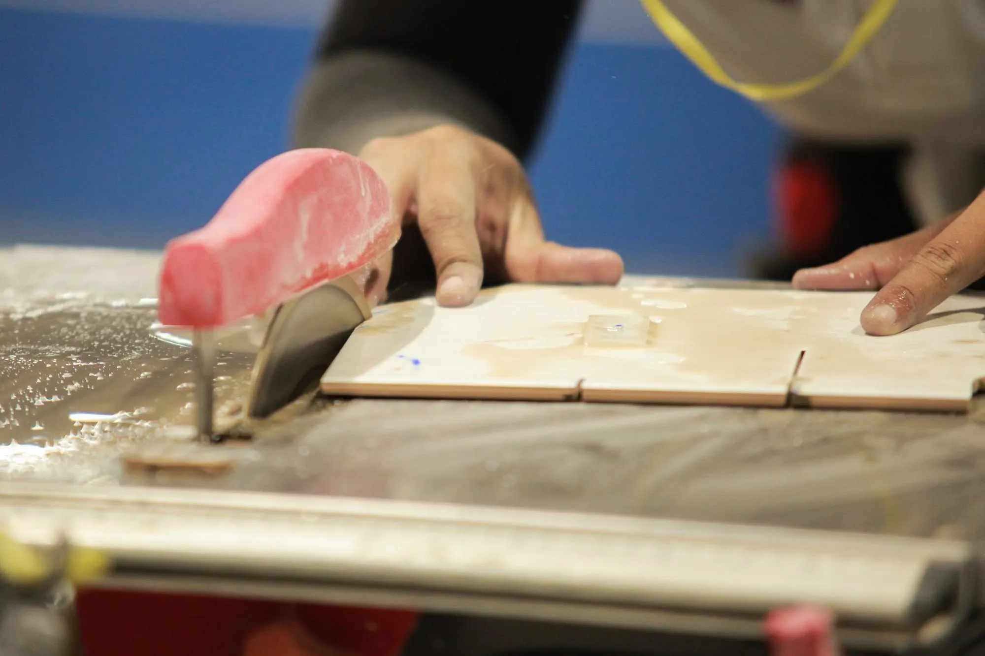 Midsection of man cutting tile